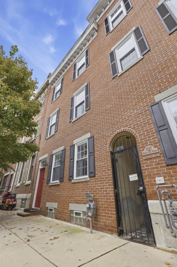 Charming brick building with black shutters and white trim in a city neighborhood.